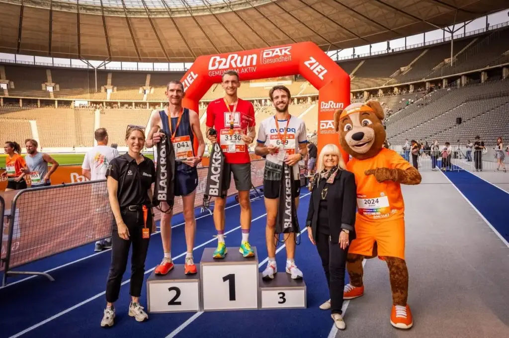 Firmenlauf Berlin - B2Run am 17.9.2024 im Berliner Olympiastation. Die Sieger. Im Hintergrund links das ETL Shirt mit dem Grafik Logo der vier Läufer, getragen von Online Redakteur Armin Ceric.